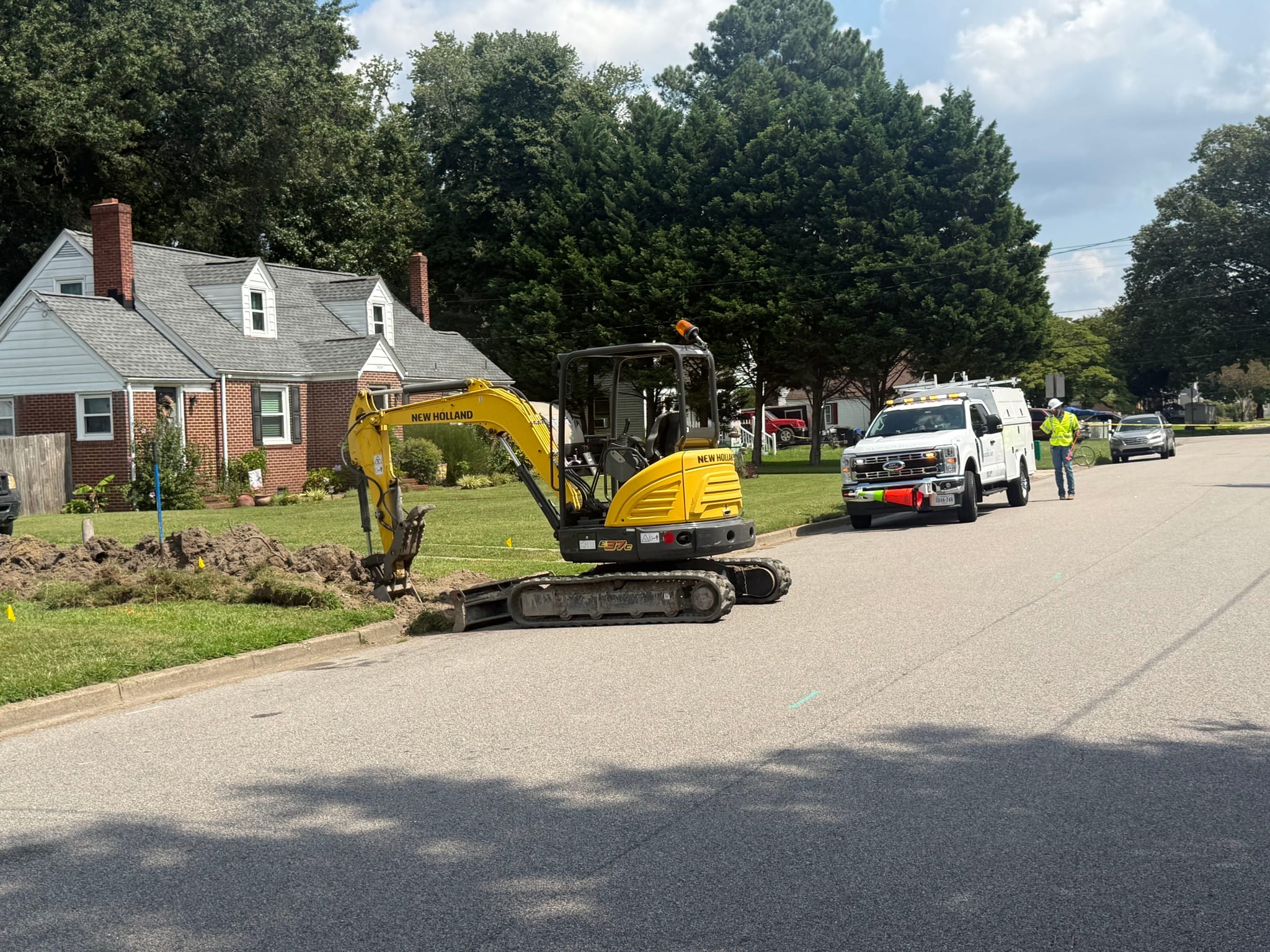Mini excavator digging a water line replacement trench on a residential street in Portsmouth, VA