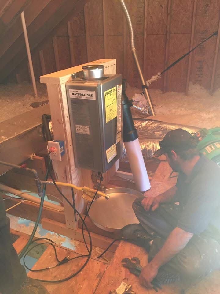 Newman's Plumbing technician installing a natural gas tankless water heater in an attic in Portsmouth, VA